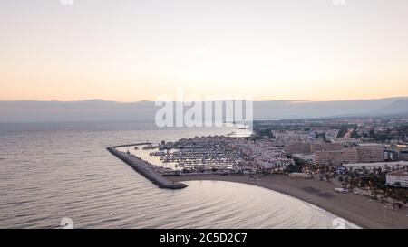Herrlicher Sonnenuntergang in puerto banus, marbella. Orange und weiches Orange am Himmel mit einem ruhigen Meer und das Lichthaus in der Szene Stockfoto