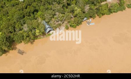 Luftaufnahme eines Teils des kinabatangan Flusses mit Haus umgeben von Dschungelbäumen und einem kleinen Dock mit Booten Stockfoto