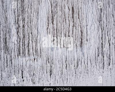 Trockene weiße Striche Farbe tropft auf Glas. Alte Grunge-Textur. Deckendes gefärbtes Fenster Stockfoto