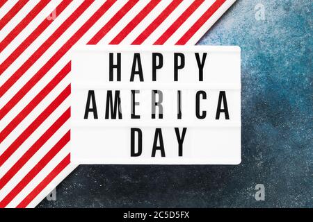 HAPPY AMERICA DAY in Leuchtkasten auf rot-blauem Hintergrund geschrieben. Draufsicht, Kopierbereich. Konzept des Unabhängigkeitstages Stockfoto