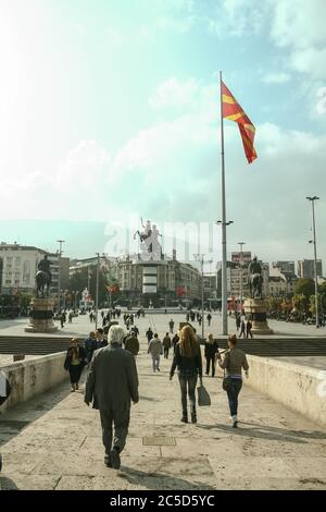 SKOPJE, MAZEDONIEN - 25. OKTOBER 2011: Mazedonische Menschenmenge, die die Steinbrücke hinunter zur Statue Alexander des Großen auf dem Hauptplatz von Skopje geht Stockfoto