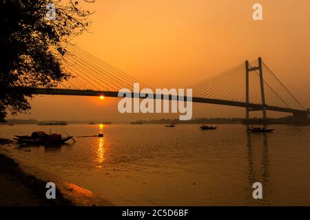 Zweite Hoogly Brücke bei Kolkata mit Sonnenuntergang und einem Boot Stockfoto
