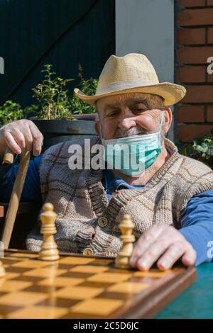 Älterer Mann, der während der Coronavirus-Epidemie in Quarantäne Schach spielt Stockfoto