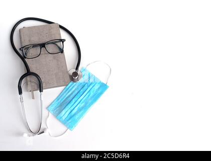 Arbeitsplatz eines Arztes. Laptop, Stethoskop, Pillen, Thermometer, Schutzmaske in blauen Farbtönen auf einem weißen Tisch. Stockfoto