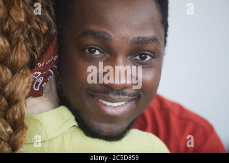 Porträt eines jungen afrikanischen Mannes, der die Frau umarmt und die Kamera anlächelt Stockfoto