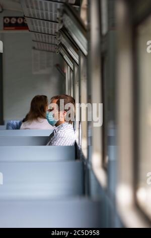 Trauriger Mann trägt eine Schutzmaske im Zug, um die Atemwege vor Coronavirus-Infektion zu schützen, covid-19. Vorbeugende Maßnahme. Neue normale. Stockfoto