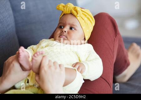 Schönes Mädchen auf den Beinen ihrer Mutter liegen, während sie auf dem Sofa zu Hause ruhen Stockfoto