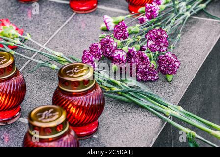 Nelken auf einer Marmorplatte Nahaufnahme und Begräbnislampen. Blumen legen. Tag der Erinnerung und Trauer. Stockfoto