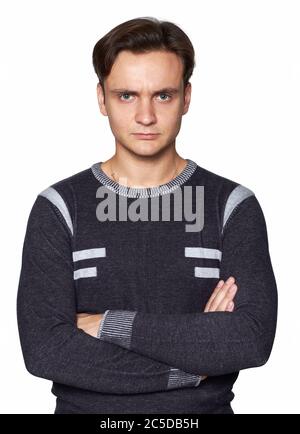 Ernst junger Mann mit gefalteten Händen. Wütend Kerl isoliert auf grauem Hintergrund Stockfoto
