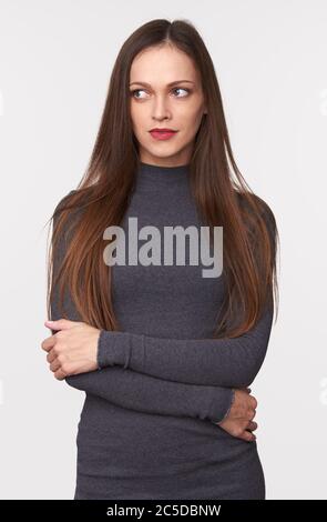 Schöne Frau mit langen braunen Haaren trägt Pullover und schaut beiseite, um Platz zu kopieren. Isoliert auf grauem Studiohintergrund Stockfoto
