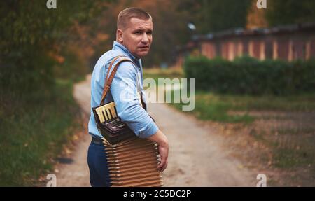 Russischer Mann mit Akkordeon. Tragbares Musikinstrument, gespielt mit Tasten und Tasten. Stockfoto