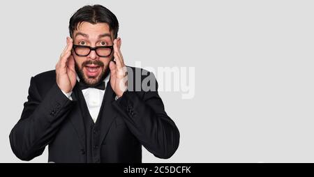 Überrascht bärtigen Mann in Smoking und Brille isoliert auf grauem Hintergrund Stockfoto