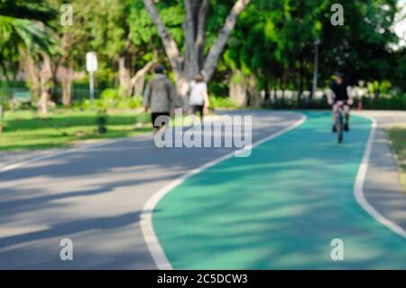 Ein verschwommenes Bild von Menschen, die in einem Park spazieren und Fahrrad fahren Stockfoto