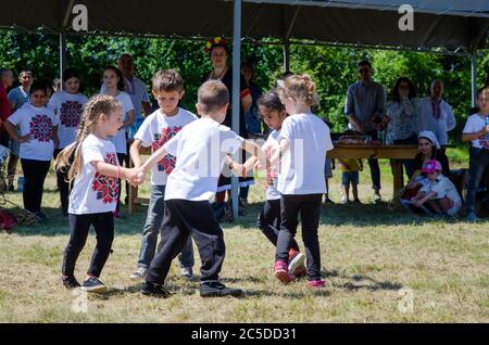 Bulgarische Kinder tanzen die Horo, um traditionelle Brauch der Weizenernte in ländlichen Dorf zu feiern. Stockfoto