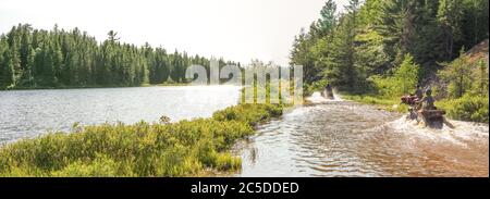 Menschen fahren ATV Quads durch Wasser. See in Ontario, Kanada. Stockfoto