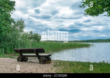 Ruhige Szene mit einer Holzbank mit Blick auf den Wutzsee in Lindow, Deutschland Stockfoto