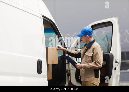 Kurier Überprüfung der Kartons im Auto vor dem Versand Stockfoto