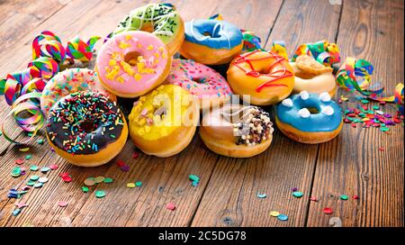 Festlicher Karneval oder Geburtstag Hintergrund mit bunten Donuts, Luftschlangen und Konfetti Stockfoto