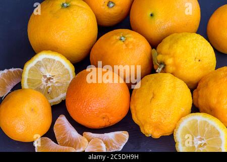 Zitrushintergrund mit Zitronen, Mandarine und Orangen isoliert auf schwarzem Hintergrund - ganz und geschnitten Stockfoto