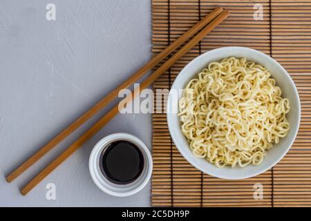 Schüssel mit einfachen gekochten Nudeln mit Essstäbchen und kleine Schüssel mit Sojasauce - Overhead-Ansicht Foto mit Text Raum Stockfoto