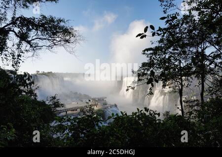Wasserwolken sprühen vom Devils Throat Wasserfall bei Iguacu Falls, durch Silhouetten von Bäumen, Brasilien, Südamerika Stockfoto
