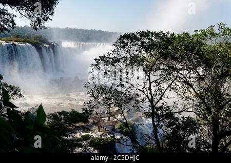 Wasserwolken sprühen vom Devils Throat Wasserfall bei Iguacu Falls, durch Silhouetten von Bäumen, Brasilien, Südamerika Stockfoto