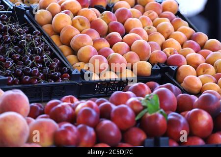 Schöne Foto von Kirschen, Pfirsichen, Nektarinen und Aprikosen auf einem Markt. Obst-Muster Stockfoto