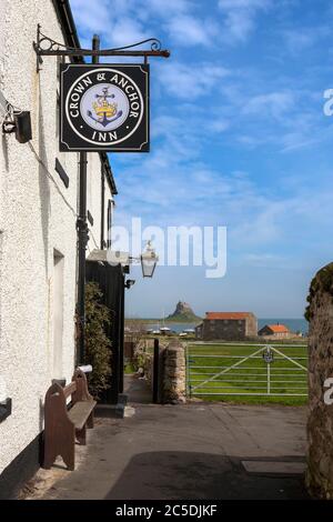 Außerhalb des Crown and Anchor Pub, mit dem Schloss in der Ferne, Holy Island of Lindisfarne, Northumberland, England, Großbritannien Stockfoto