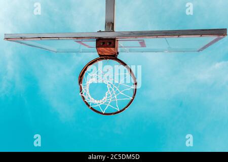 Sport und Basketball. Ansicht von unten auf den Basketballkorb. Blauer Himmel im Hintergrund. Speicherplatz kopieren. Stockfoto
