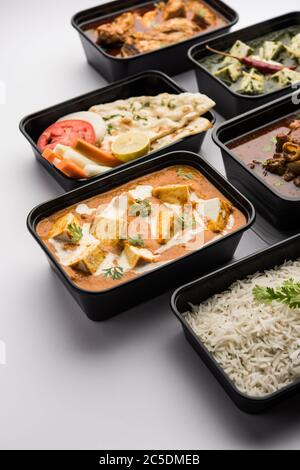 Online Food Delivery Concept Indische Paneer Butter Masala und Palak Paneer, Hammelfleisch & Huhn Curry mit Roti und Reis in Plastikbehältern, Lebensmittel wie Stockfoto