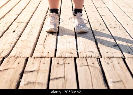 Füße eines nicht erkennbaren Läufers mit Laufschuhen auf Holzboden, Konzept von Sport und gesunder Lebensweise, Textraum Stockfoto