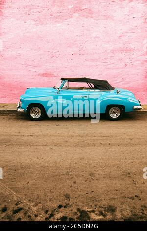 Altes blaues Auto, das an einer pinken Wand geparkt ist, Havanna - kuba Stockfoto