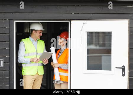 Junge Ingenieur in reflektierenden Weste im Gespräch mit Frau, während sie auf der Baustelle arbeiten Stockfoto