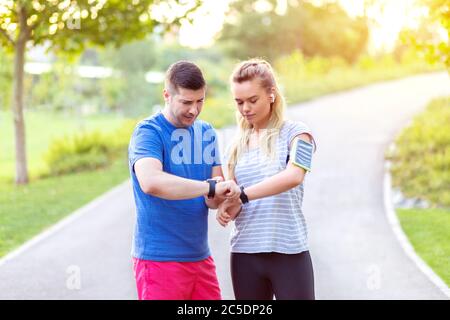 Sportlich reifes Paar, das Zeit auf Smartwatch überprüft Stockfoto