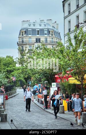 Paris, Frankreich - 18. Juni 2015: Fußgänger, die auf dem Bürgersteig vor dem Hintergrund von Bäumen und Fassaden von Gebäuden gehen Stockfoto