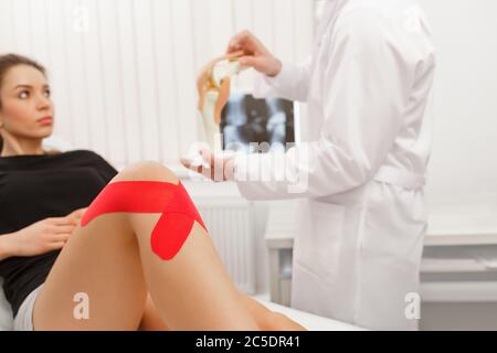 Kinesiologie Taping.Physikalischer Therapeut Anwendung von Kinesiologieband auf den Patienten Knie.Therapeut Behandlung verletzter Knie des jungen Athleten.Post traumatisch Stockfoto