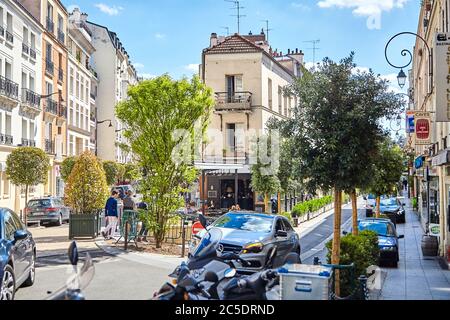 Paris, Frankreich - 19. Juni 2015: Autos in den engen, gemütlichen Straßen der Stadt geparkt. Cafe an der Ecke eines Hauses zwischen grünen Bäumen Stockfoto