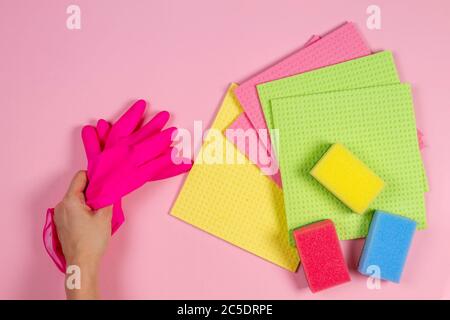 Home Reinigung Hintergrund. Frau Hand halten Gummihandschuhe, viele Schwämme auf rosa Hintergrund Stockfoto