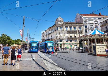 MONTPELLIER, FRANKREICH - 24. Juni 2015: Architektur des Place de la Comedie und des Karussells. Menschen, die die Straße durch Straßenbahnlinien überqueren. Öffentliche Stadt tra Stockfoto