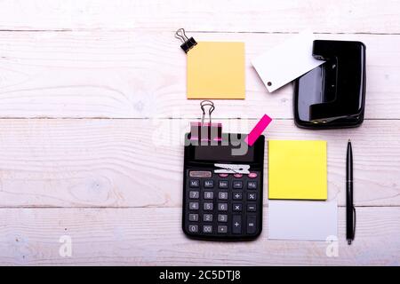 Business-Accessoires und Ideen-Konzept. Lesezeichen der rosa Farbe in der Nähe Stift und Lochstanze auf weißem Holzhintergrund. Schreibwaren und Taschenrechner. Visitenkarte mit leerem Platz und gelben Haftnotizen Stockfoto