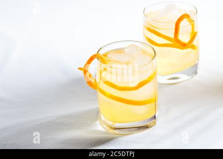 Sommerliche erfrischende Cocktails, Limonade oder Mojito mit Orangenschale und Eis in einem Glas auf weißem Hintergrund. Für Text platzieren. Hartes Licht Stockfoto