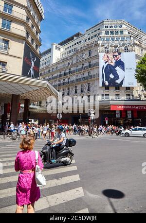 Paris, Frankreich - 29. Juni 2015: Boulevard Haussmann. Eine Frau an einer Fußgängerüberführung vor dem Fassadengebäude der Galeries Lafayette Stockfoto