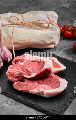 Zwei Stücke Schweinefleisch auf einem Schieferteller auf einem grauen Hintergrund. Kopierraum, Foto für Lebensmittelgeschäfte Stockfoto