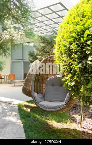 Gepflegter grüner Garten. Tolle gemütliche Unterkunft. Korbstuhl Nest. Stockfoto