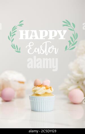 Selektiver Fokus von Cupcake mit ostereiern auf grauem Hintergrund mit fröhlicher Osterdarstellung Stockfoto