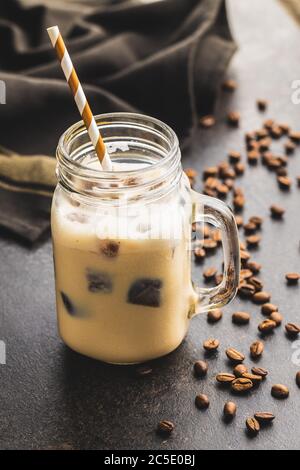 Eiskaffee mit Kaffeeeiswürfeln auf schwarzem Tisch. Stockfoto