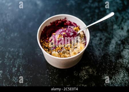 Take Away Vegane Lebensmittel Acai Schale mit Mandelmilch, Erdnussbutter, Banane, Buchweizen Müsli, Chia Samen und Schokoladenstücke in Karton Schüssel. Gesunde Org Stockfoto