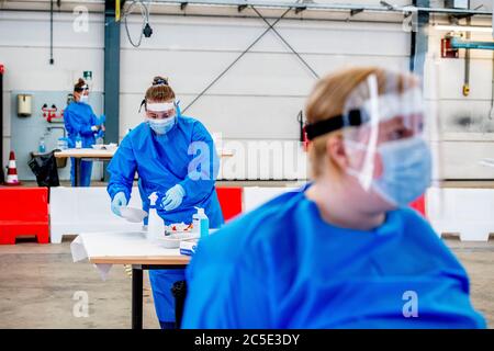 Ein Gesundheitsarbeiter trägt einen persönlichen Schutzanzug (PSA) gesehen Desinfektion der Testausrüstung am Drive-Thru.Dutch Regierung Gesundheitsarbeiter machen Drive-Thru Coronavirus-Tests an einem Drive Inn Teststandort von Menschen, die Verdacht auf die Coronavirus-Krankheit oder Beschwerden haben. Die Ergebnisse sind fertig und werden innerhalb von 2 Tagen telefonisch weitergegeben. Stockfoto