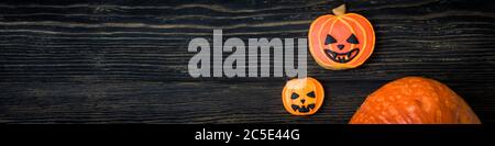Halloween Hintergrund mit Kürbis und Cookies. Horizontales Banner mit Halloween-Objekten auf einer dunklen strukturierten Holzplanke mit Kopierfläche. Draufsicht auf V Stockfoto