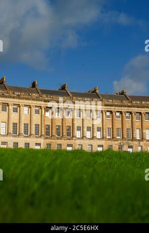 Blick auf den Royal Crescent in Bath, Somerset mit üppig grüner Wiese im Vordergrund und blauem Sommerhimmel im Hintergrund. Stockfoto